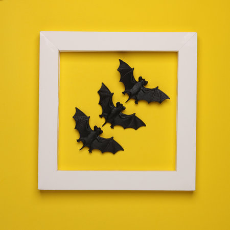 Plastic bats in white frame on yellow background. Creative layout. Halloween. Minimalismの写真素材