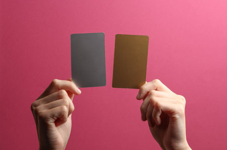 Golden and metal business cards in a female hands on a pink backgroundの写真素材