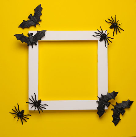 Plastic bats and spiders in white frame on yellow background. Creative layout. Halloween. Minimalismの写真素材