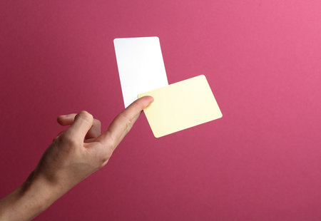 Golden and metal business cards in a female hand on a pink background