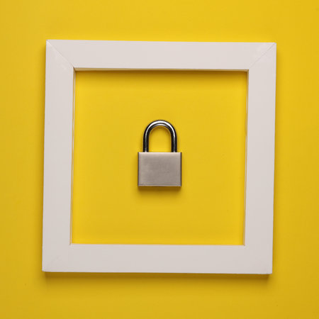Metal lock in white frame on yellow background. Creative layout. Minimalismの写真素材