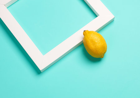 Lemon with white square frame, blue background. Aesthetic minimal still life. Food Concept photo....