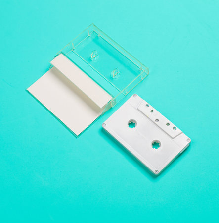 Retro 80s audio cassette and box with blank label on blue background. Music concept, mockup for...