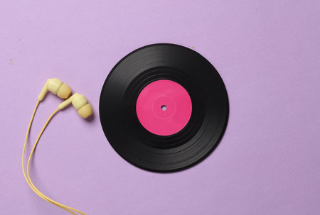 Vinyl record with headphones on magenta pastel background. Top view