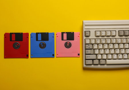 Retro keyboard and floppy disks on yellow background. Top viewの写真素材