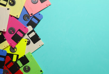 Colored floppy disks on a blue background. Retro technology. Top view. Copy space
