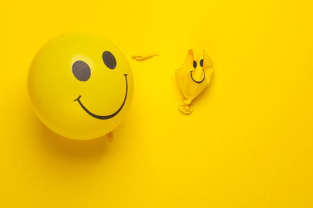 Yellow balloons with smiling face on yellow background. Mental problemsの写真素材
