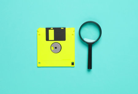 Floppy disk with a magnifying glass on a blue background. Recovery, data search