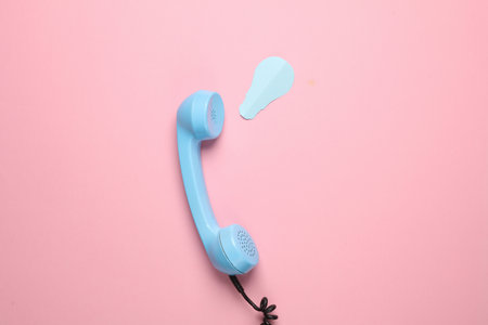 Retro telephone receiver with paper cut light bulb on pink background. Creative layout, minimalism. Conceptual photoの写真素材