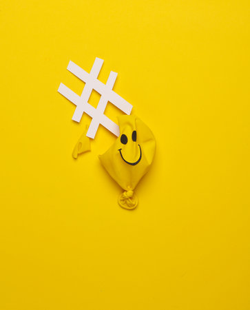 Yellow Burst balloon with smiling face and hashtag on yellow background. Mental problems. Creative layoutの写真素材