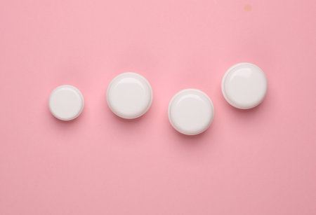 Jars of cream on a pink background. Top view. Mockup, template for designの写真素材