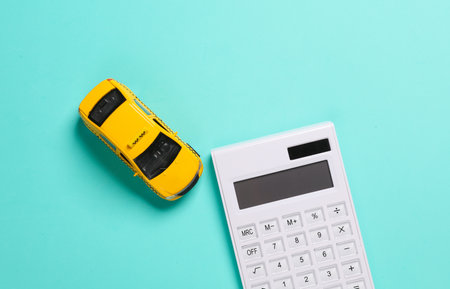 Calculator with a toy taxi car on blue background. Top viewの写真素材
