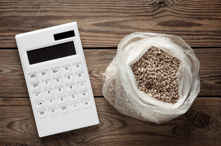 Calculator and grains of wheat on a wooden table. Food pricesの写真素材
