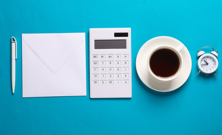 Calculator and envelope, coffee cup, alarm clock on blue background. Business cocnept. Flat lay. Top viewの写真素材