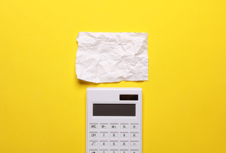 Calculator with a crumpled piece of paper on a yellow backgroundの写真素材