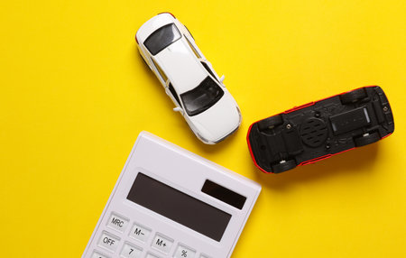 The cost of repairing a car after an accident, insurance. Calculator with toy cars, yellow background. Top viewの写真素材