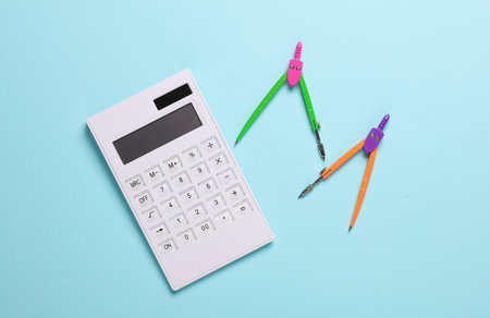 Calculator and Stationery Compasses on blue background. Top view