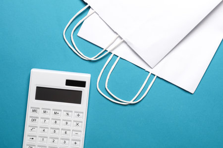 White Calculator with shopping bags on a blue background. Sale conceptの写真素材