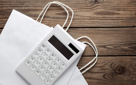 White Calculator with shopping bags on wooden background. Sale conceptの写真素材