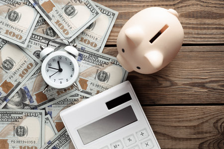 Many dollar bills with alarm clock and calculator, piggy bank on wooden table. Business concept....