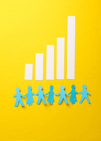 Paper-cut chain of people and columns of graphics on a yellow background. Demographic analysis, sociological statisticsの写真素材