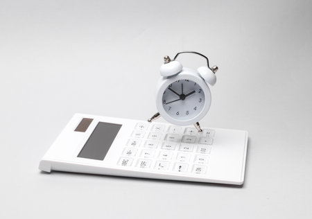 Calculator with an alarm clock on gray backgroundの写真素材
