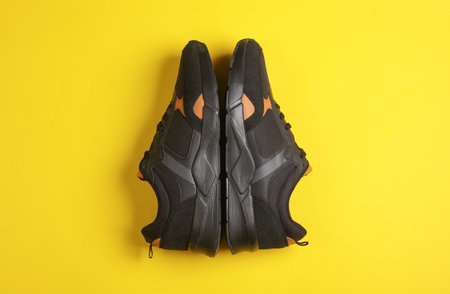 A pair of black running shoes on a yellow background. Top viewの写真素材