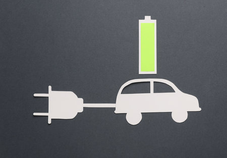 Paper-cut car with an electric plug and a fully charged battery on a gray background. Electric car, modern technology, eco conceptの写真素材