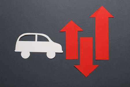 Paper-cut car icon with red arrows on a dark background