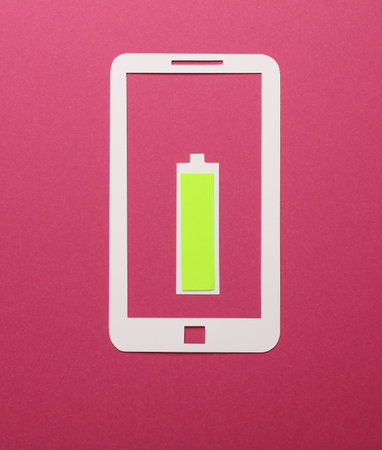 Paper-cut smartphone icon with fully charged battery on a pink backgroundの写真素材