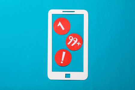 Paper-cut smartphone and notification icons on a blue backgroundの写真素材