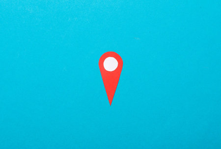 Paper cut red geolocation point (location pin) on blue background