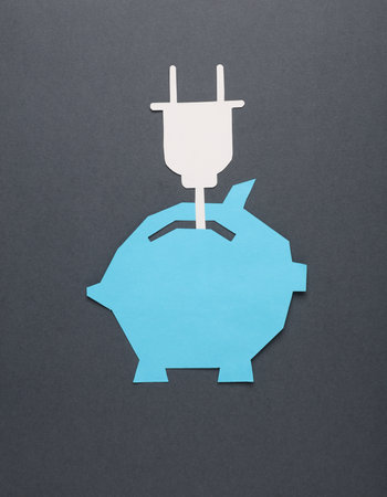 Paper-cut piggy bank with electric plug on a dark gray background. Business cognept