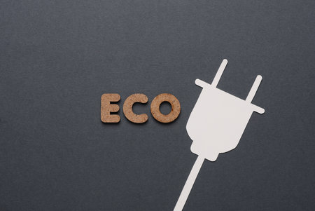 Green energy. The word eco and paper-cut electric plug on dark gray background