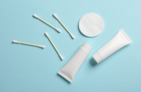 Cream tubes with cotton pads and ear buds on a blue backgroundの写真素材