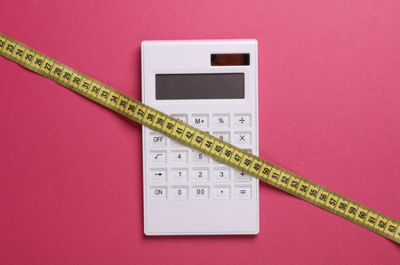Measuring tape with calculator on pink background. Weight loss, diet conceptの写真素材