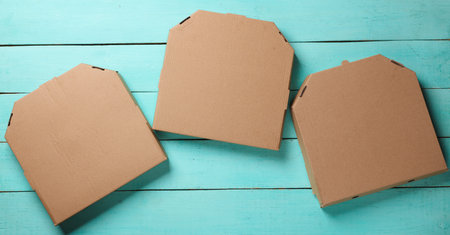Cardboard craft pizza boxes on blue wooden background. Top view.の写真素材