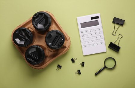 Calculator and cups of coffee, paper binders on a green background. Top view. Business coincept
