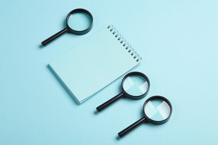 Notepad with magnifiers on a blue background. Education, business conceptの写真素材