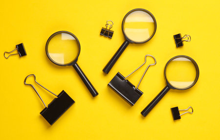 Magnifiers and paper binders on yellow background. Top viewの写真素材