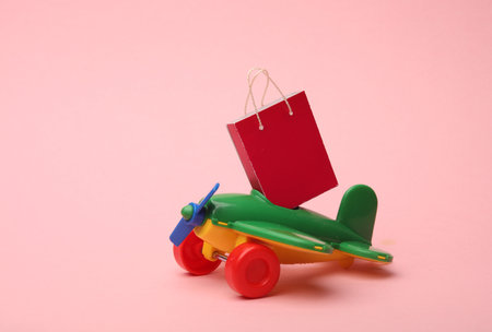 Toy air plane and Miniature shopping bag on a pink background. Travel and shopping conceptの写真素材