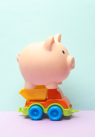 Toy dump truck with piggy bank on a pastel backgroundの写真素材