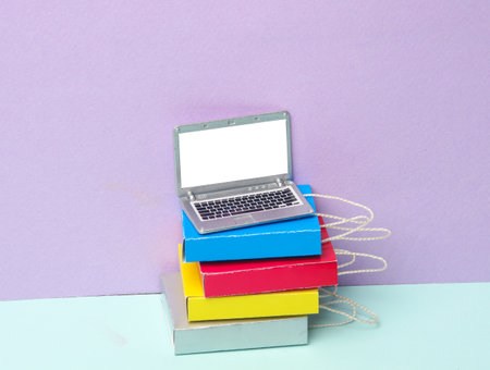 Miniature laptop with shopping bags on pastel background