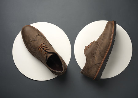 Leather brogues on a white circles. Dark gray background. Top view. Creative idea. Fashion conceptの写真素材
