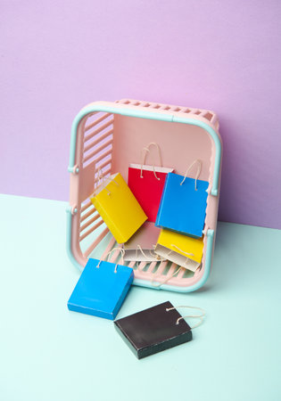 Miniature shopping bags in supermarket basket on pastel background. Black Friday, world shopping...