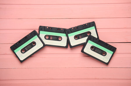 Retro 80s audio cassettes on pink wooden boards. Top view
