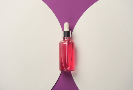 Pink bottle of face serum on purple background with white circles. Template for design. Beauty conceptの写真素材