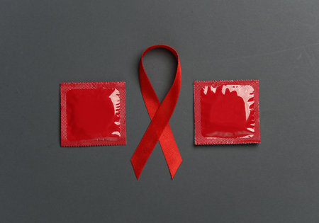 Red awareness ribbon with condoms on dark background. Safe sex. Worlds HIV Aids Dayの写真素材