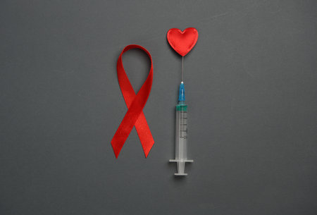 Red awareness ribbon with heart, syringe on dark background. Worlds HIV Aids Dayの写真素材