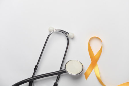 Yellow ribbon, childhood cancer awareness day symbol and stethoscope on white backgroundの写真素材